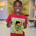 在学校的走廊里，一个年轻的学生举起他们的艺术作品，微笑着拍照